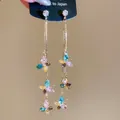 Detailed view of long tassel earrings with colorful butterfly-shaped rhinestones in gold. - Gold-Multicolor