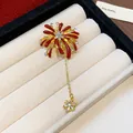 Close-up detail of firework-shaped brooch with red enamel and sparkling crystals in jewelry box - Fireworks Flower (Gold-Red)