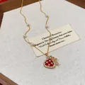 Close-up detail of a gold-plated necklace featuring a red fortune bag pendant and pearls - Necklace / Gold And Red