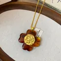 Detailed macro shot of vintage amber flower pendant with textured golden floral center. - Flower Dangle Style / Gold & Coffee