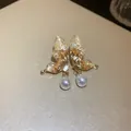 Dettaglio di eleganti orecchini a farfalla dorati con cristalli e perle a goccia. - Orecchini a perla con farfalla / Champagne