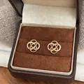 Detailed macro view of gold hollow flower earrings with sparkling zirconia in a box - Hollow Flower Style (HE30635) / Gold