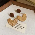Primo piano di orecchini geometrici in stile Maillard retrò in oro e marrone su carta - Stile Orecchini Geometrici (5944763480733)