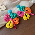 Detailed macro view of colorful handmade raffia woven flower earrings with silver needles - Flower Shape / Colorful