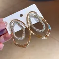 Primer plano de pendientes ovalados dorados con detalles de cristaux brillantes - Dorado