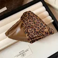 Close-up view of a large leopard print and leather triangle hair claw clip on a tray - Style 1 Claw Clip - Coffee