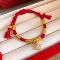 Detailed view of a red braided rope bracelet with golden beads and a rocking horse charm - White Enamel Painted Horse (Style 22)