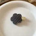 Detail view of a sweet black flower hair clip featuring white polka dots and a gold base - #1 Duckbill Clip - Black Polka Dot Flower