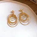 Detailed macro view of stylish gold multi-layer geometric hoop earrings on a white plate - Small / Gold