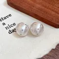 Detail view of silver brushed spherical stud earrings with star rhinestone inlay - Stud Earrings / Silver