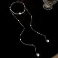 Vista dettagliata di un'elegante collana lunga con nappe di perle e design minimalista - Argento