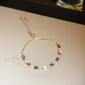 Elegant gold adjustable bracelet featuring colorful zircon stones in geometric design. - Purple Rectangle