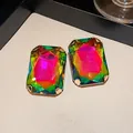 Close-up detail of large iridescent rectangular stud earrings with gold-tone claw setting. - Silver Needle Studs / Gold-Multicolor