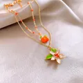 Elegante collana d'oro con ciondolo arancione e fiore su tessuto di seta champagne. - 63# Collana-Fiore (Placcato in Oro Vero)