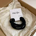 Gros plan d'élastiques à cheveux noirs sur un emballage carton minimaliste HenJu - Noir