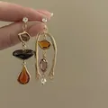 Detail view of vintage asymmetric gold earrings with amber resin and zircon accents. - Asymmetric Style (1#)
