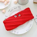 Fun red monster zipper pencil case with large googly eyes shown on a white ceramic plate - Red