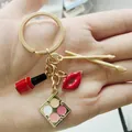 Porte-clés en alliage avec charms thème maquillage: rouge à lèvres, lèvres et brosses. - Doré