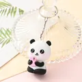 Close-up of a cute cartoon panda keychain holding a pink phone charm - Panda with Pink Phone