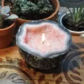 Close-up of a lit pink crystal geode candle bowl placed on a carved wooden surface - Large Size 6x12 / Light Pink