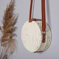 Détail d'un sac à bandoulière rond en paille blanche avec une lanière en simili cuir brun - Blanc