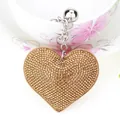 Close-up of heart-shaped keychain featuring densely set golden rhinestones on leather. - Silver + Khaki