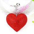 Dettaglio macro di un portachiavi a forma di cuore con strass rossi e catena d'argento - Argento + Rosso Vivace