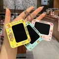 Detail showing three colorful mini doodle board keychains held by hand with cute cartoon designs. - Yellow