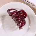 Elegant wine red hollow spiral hair claw clip presented on a white porcelain plate - Purple