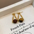 Eleganti orecchini pendenti rétro color oro con perle occhio di tigre su base materica - Stile con Perlina Pendente Vintage