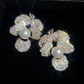 Elegante goudkleurige bloemknopjes met witte parel en sprankelende pavékristallen. - Stijl 18 (HE32568)