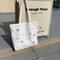 Vue détaillée du sac fourre-tout en toile crème avec motifs de nuages brodés colorés - Style Nuage Bleu Clair (Sac à Bandoulière)