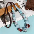 Close-up of ethnic ceramic sweater necklace with blue mottled beads and brown cord - X1098 Blue Red Ball