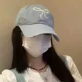 Stylish light blue baseball cap featuring a white bow embroidery worn by a female model - Blue