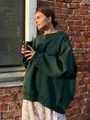 Detail of an oversized dark green crewneck sweatshirt in an outdoor lifestyle setting - Dark Green