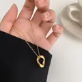Elegant minimalist gold-plated oval hollow pendant necklace displayed on a hand and black sleeve - Gold