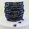 Macro detail view of royal blue beaded flower chain on a white spool for DIY jewelry - Gold Royal Blue