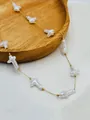 Detailed macro view of a delicate gold chain necklace with white baroque cross-shaped pearls. - Gold Cross Style