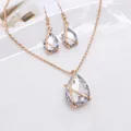 Detailopname van elegante goudkleurige ketting en oorbellen met kristallen waterdruppel - Sieradenset met Waterdruppels / Wit