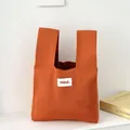 Borsa da polso in maglia arancione vibrante con etichetta minimalista per regali. - Arancione Hilldi