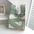 Borsa in maglia rosa e verde con vivaci motivi a cuore su una superficie bianca - Cuore Ondulato Rosa Verde