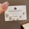 Detailed macro view of graduated white pearl stud earring set on display card - 16# Pearl Earrings (three-piece Set Thickened With Genuine Gold Plating)