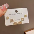 Close-up of "m" shaped gold stud earrings with rhinestones on a display card. - 18# Gold-plated Zircon M Letter Three-piece Set (thickened Real Gold Plating)