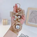 Elegante portachiavi a camelia con perle e dettaglio fiocco in nastro beige doppio. - Cachi