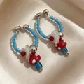 Handmade vintage style beaded hoop earrings with red mushroom and white flower charms. - Red Blue Mushroom Contrast Earrings (2606132)