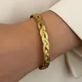 Vintage bohemian style gold stainless steel braided cuff bracelet on woman's wrist - Three Strand Weave (X317)
