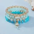 Nahaufnahme von mehrlagigen Boho-Armbändern mit türkisen Perlen und Blumenanhänger. - Grün