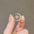 Nahaufnahme eines goldenen Mond- und Sternrings mit funkelnden Zirkoniasteinen. - Stern Mond Stil / Gold