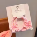 Vista dettagliata di elastici per capelli rosa a fiore su carta - Grande elastico sottile fiori di pesco