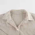 Detailaufnahme eines beigen Gingham-Pyjamahemdkragens mit M-Etikett und weißem Knopf. - S / Oberteil Und Unterteil / Beige Kariert
